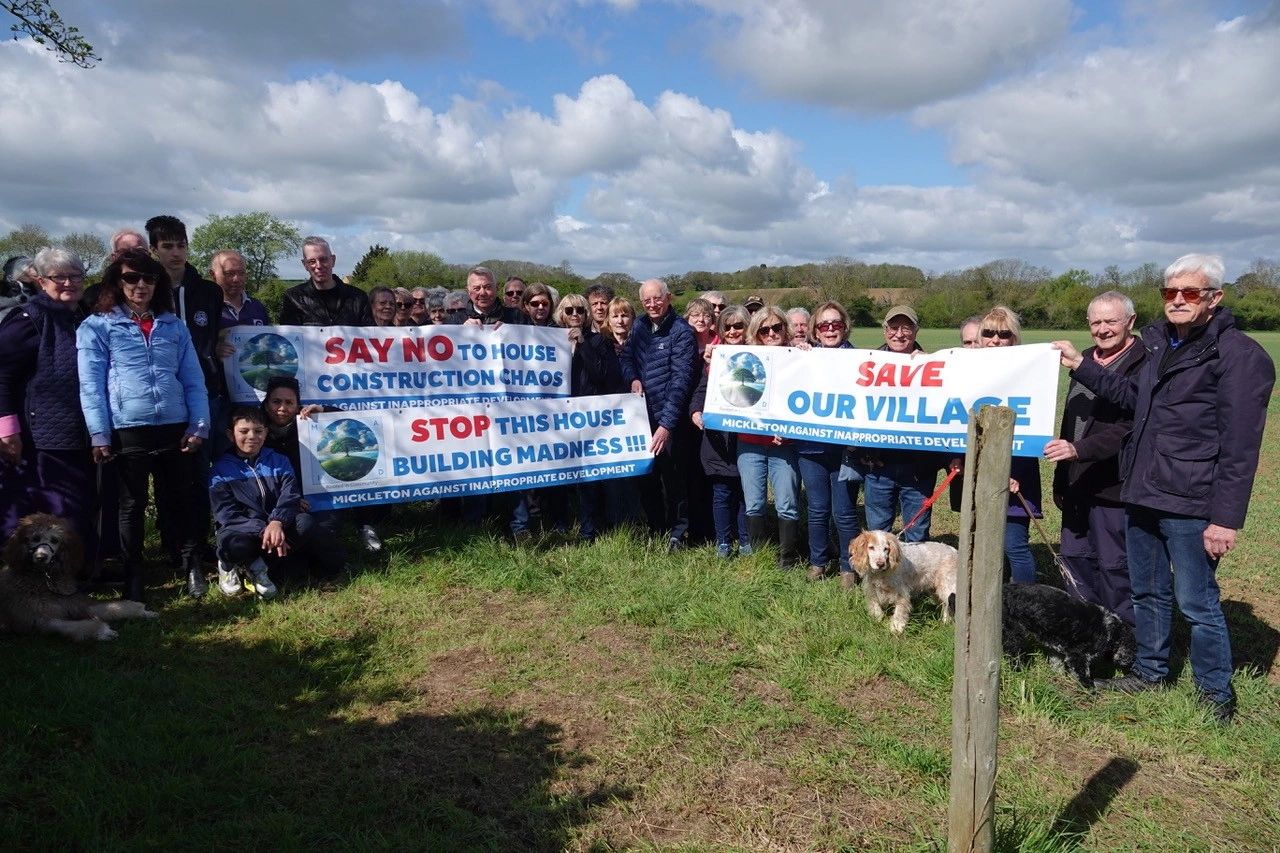 Community protest against house building in their village with banners and dogs.