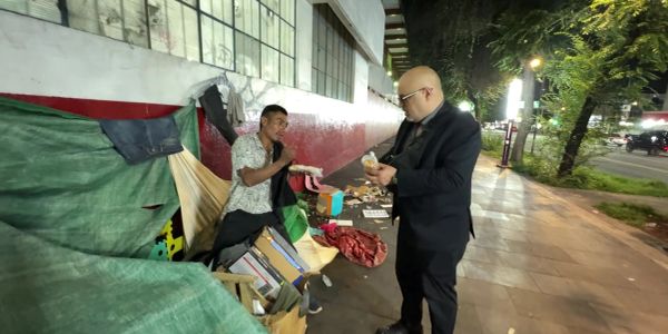 Dos hombres compartiendo comida en la calle por la noche.