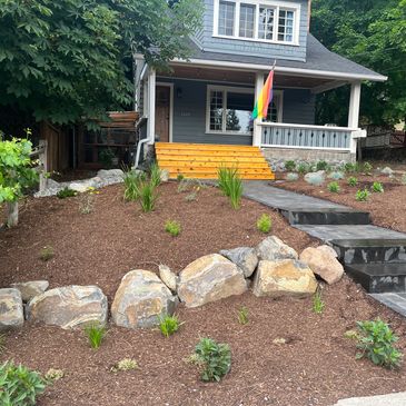 Front yard installation with boulder retaining wall and paver walkway.