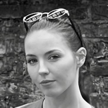 Black and white portrait of a woman with sunglasses on her head.