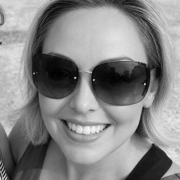 Smiling woman wearing large sunglasses outdoors.