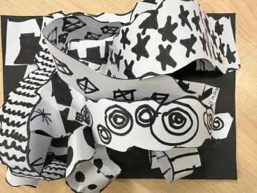 Black and white abstract paper strips with various patterns on a black base.
