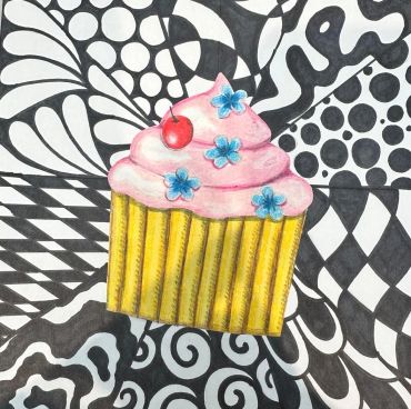Colorful cupcake with pink frosting and blue flowers on a black and white patterned background.