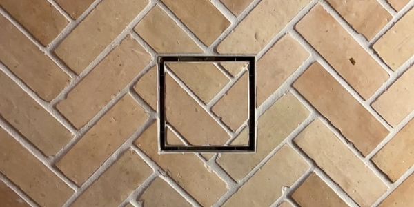 Square metal frame on a herringbone-patterned brick wall.