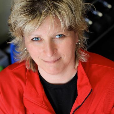 Smiling woman with blonde hair wearing a red jacket.