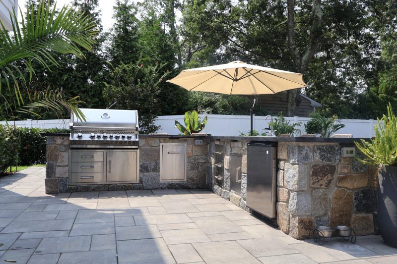 Stone outdoor kitchen with built-in grill at a Long Island backyard
