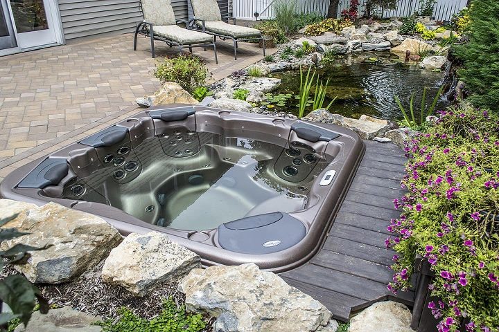 Hot tub set into a deck beside a planted pond