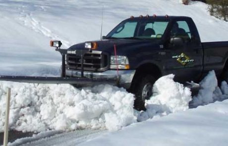 Deck and Patio Company truck with plow clearing snow from a Long Island driveway