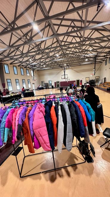 Colorful winter coats hanging on a rack in a gymnasium.