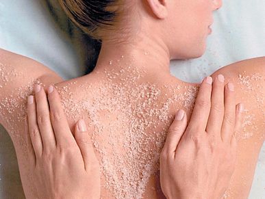 Woman receiving sea salt body scrub back massage