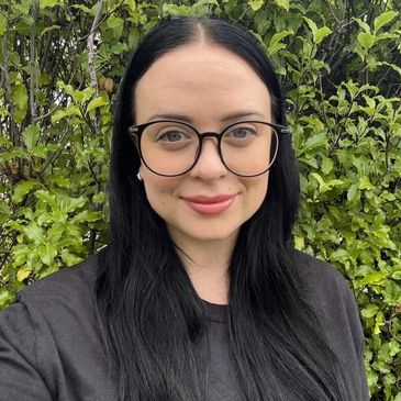 Bree, receptionist from Cannabis Doctors Tasmania, pictured on front of a green bush