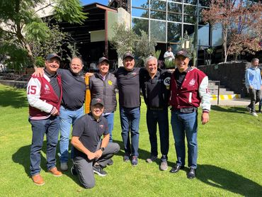 Grupo de hombres posando en un jardín soleado.