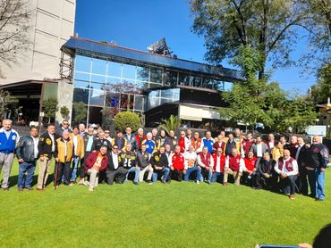 Gran grupo posando al aire libre frente a un edificio moderno.