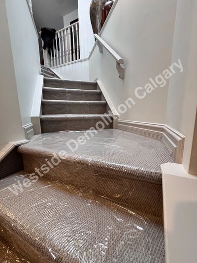 Carpeted stairs covered with protective plastic wrap in a home interior.