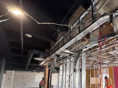 Construction workers dismantling an interior wall inside a building.