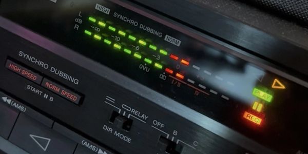 Close-up of a vintage audio cassette player's control panel with illuminated play and record indicators.