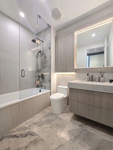 Modern bathroom with glass shower and marble floor.