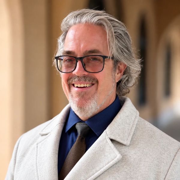 Smiling middle-aged man with gray hair and glasses.
