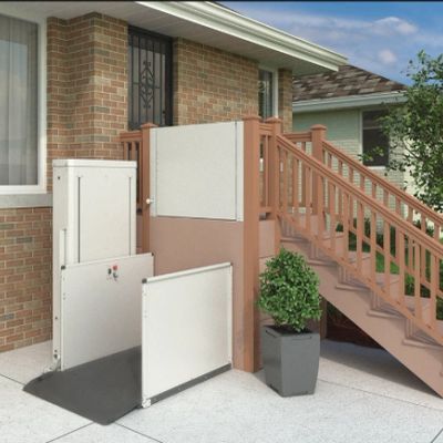 Outdoor wheelchair lift installed beside a house staircase for accessibility.