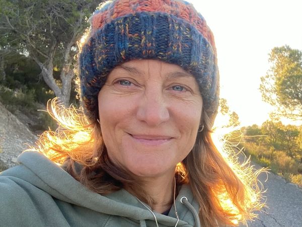 Smiling woman wearing a knit hat outdoors in natural sunlight.