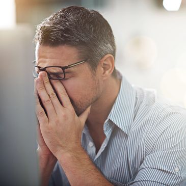 Arbeitender Mann sitzt müde am Schreibtisch.