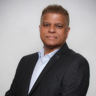Professional man in a dark blazer posing against a plain background.