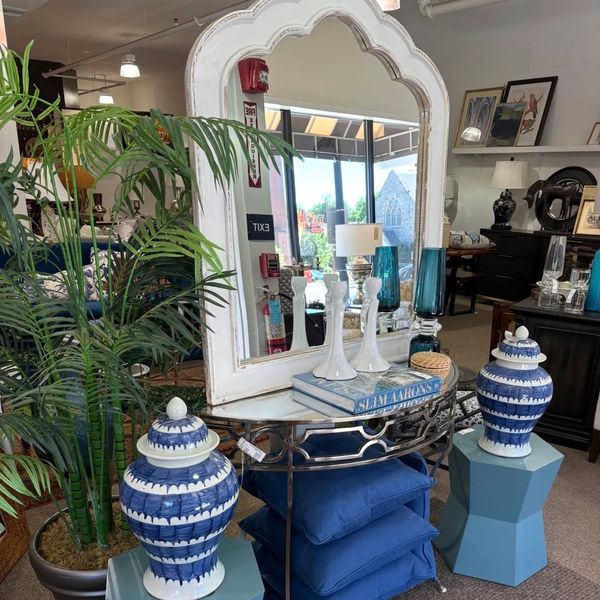 Elegant interior setup with blue and white vases, a large mirror, and cushions.