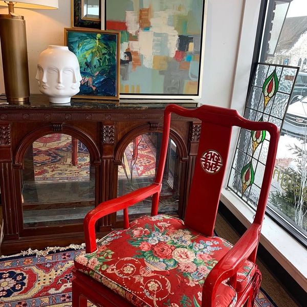 Red wooden chair with floral cushion in a decorated room.