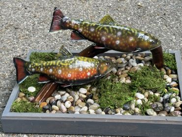 Decorative fish sculpture on pebbles and moss.