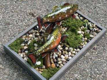 A display of two fish figures on pebbles and moss.
