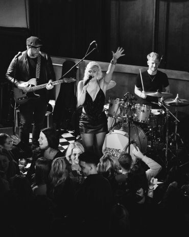 Black and white photo of a live band performing on stage with an energetic singer and crowd.