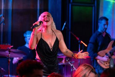 Female singer passionately performing on stage with band.