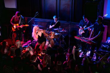 A vibrant live band performs energetically on stage in front of a lively crowd.
