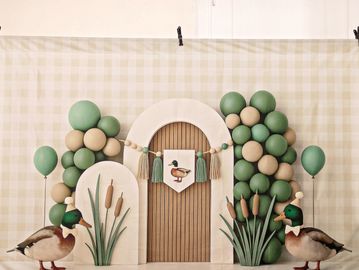 Decorative arch with duck-themed balloons and two ducks nearby.
