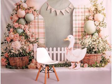 Cozy pastel floral and balloon backdrop with a white chair and duck decoration.