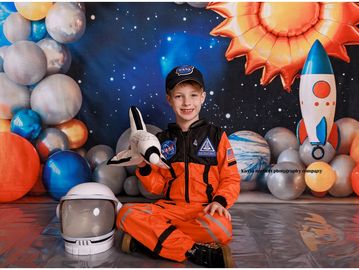 A boy dressed as an astronaut holding a toy space shuttle.