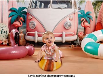 Happy baby on a surfboard with summer decorations.