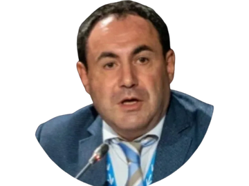 Man in blue suit speaking into a microphone.