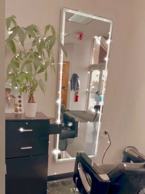 Modern salon corner with illuminated mirror and black styling chair.