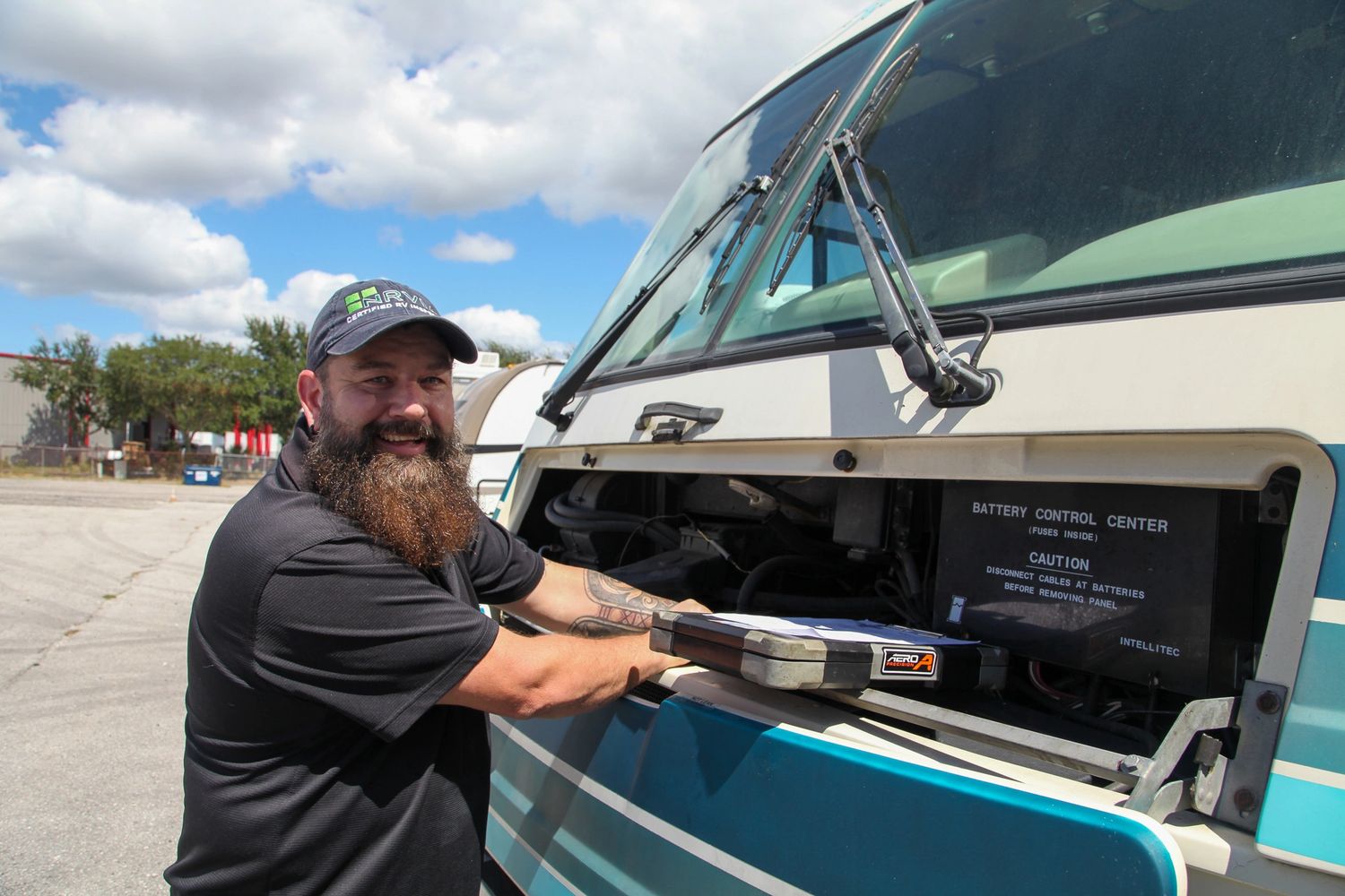 Man smiling in front of an RV and repairing the vehicle.