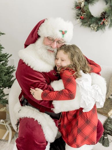 A girl hugs Santa Claus with joy.
