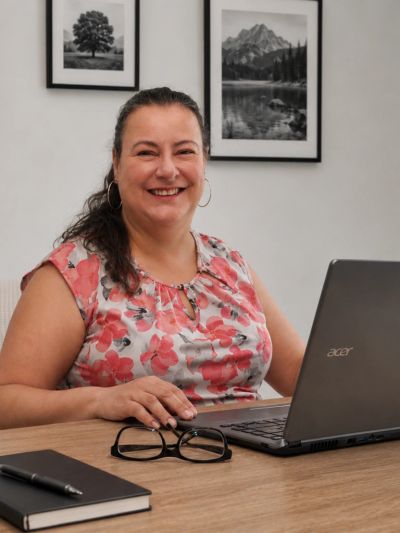 Smiling woman working on a laptop at a desk.