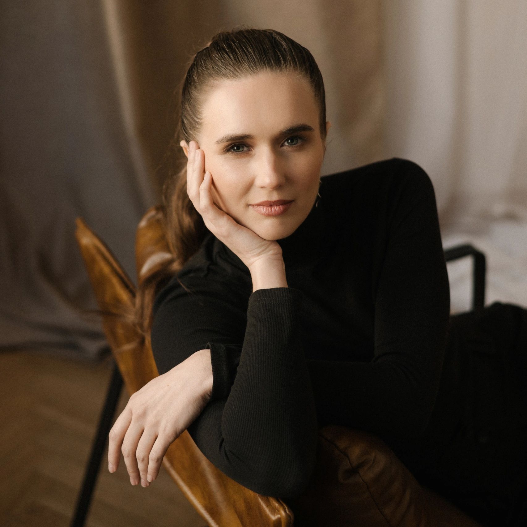 Portrait of a woman with a calm expression resting her face on her hand.