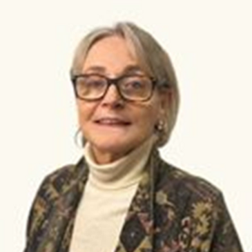 Smiling elderly woman wearing glasses and a patterned jacket.