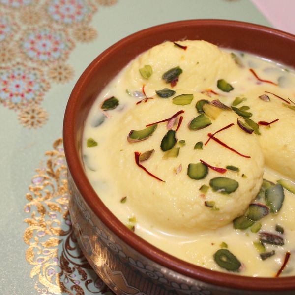 Bowl of ras malai garnished with pistachios and saffron.