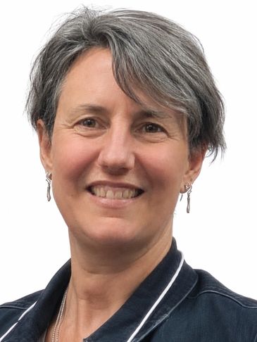 Smiling woman with short gray hair and earrings.