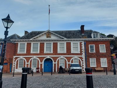 Historic brick building with blue doors and cobblestone courtyard.