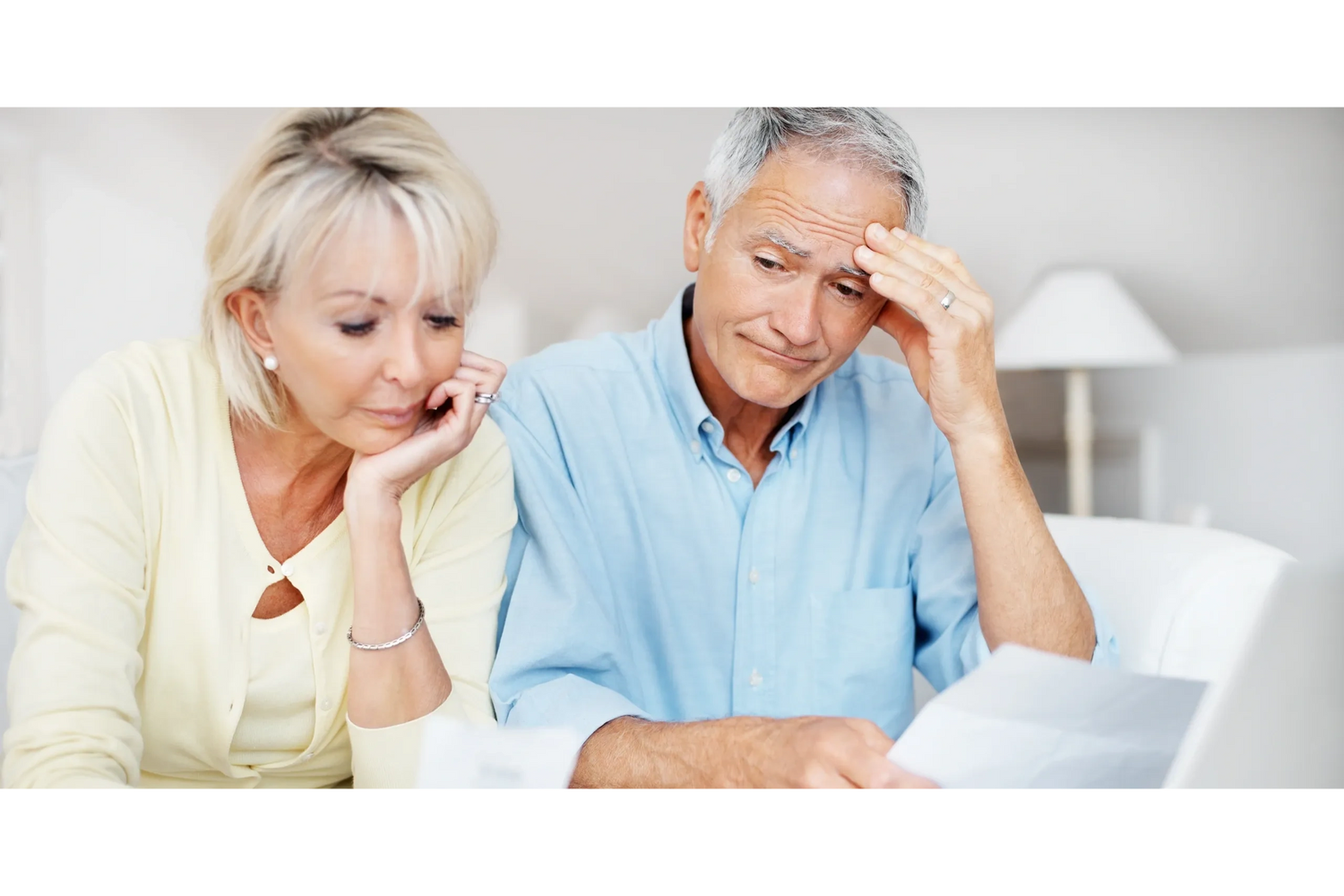 Worried elderly couple reviewing bills or documents together.
