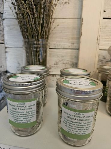 Glass jars labeled for making flu shots with elderberry powder, echinacea, ginger, and honey.