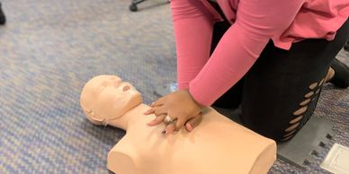 A woman practicing CPR on a mannequin